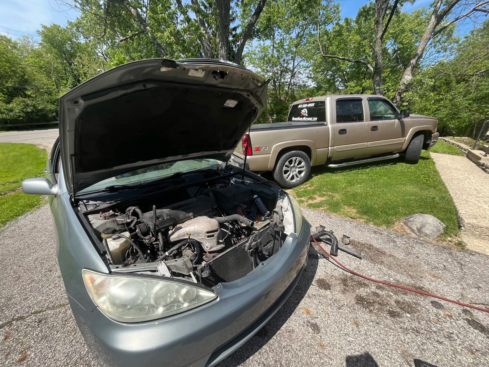 Vehicle with its hood open for mobile maintenance in a driveway