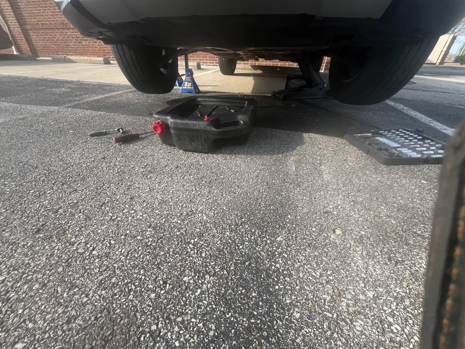 Oil drain pan positioned beneath a safely supported vehicle