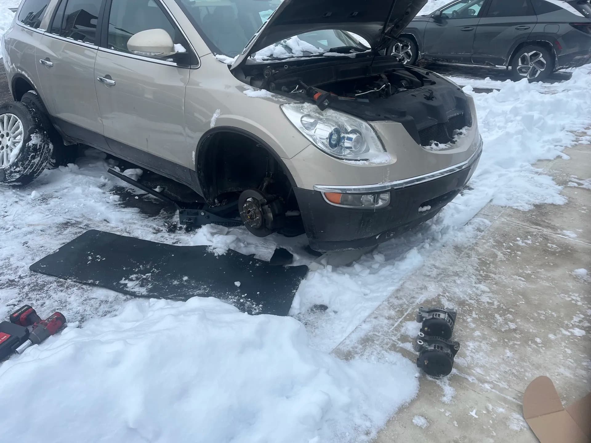 Mobile auto repair performed beside a vehicle in snowy conditions